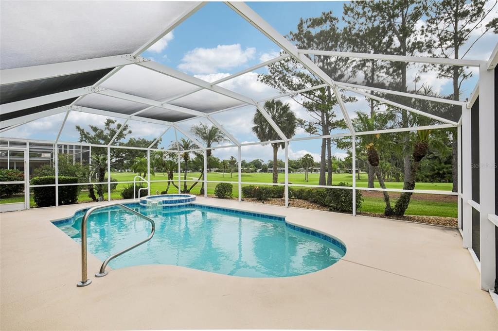A screened-in swimming pool and spa overlook a green golf course under a blue sky — 530 MAGELLAN DRIVE, SARASOTA, FL