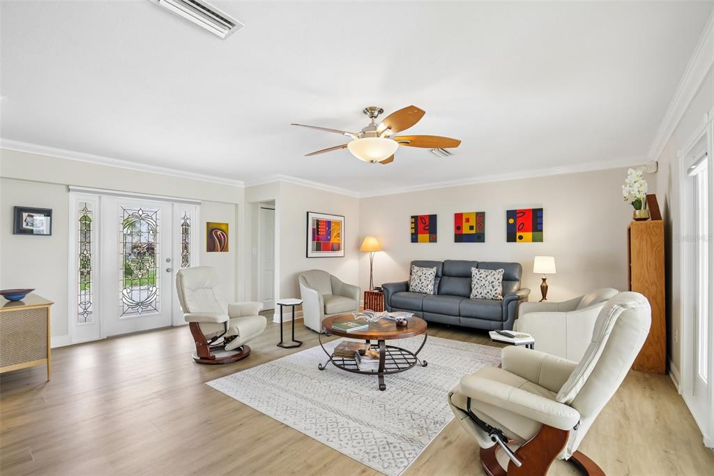 A living room features light wood flooring, a ceiling fan, and a gray sofa set — 530 MAGELLAN DRIVE, SARASOTA, FL
