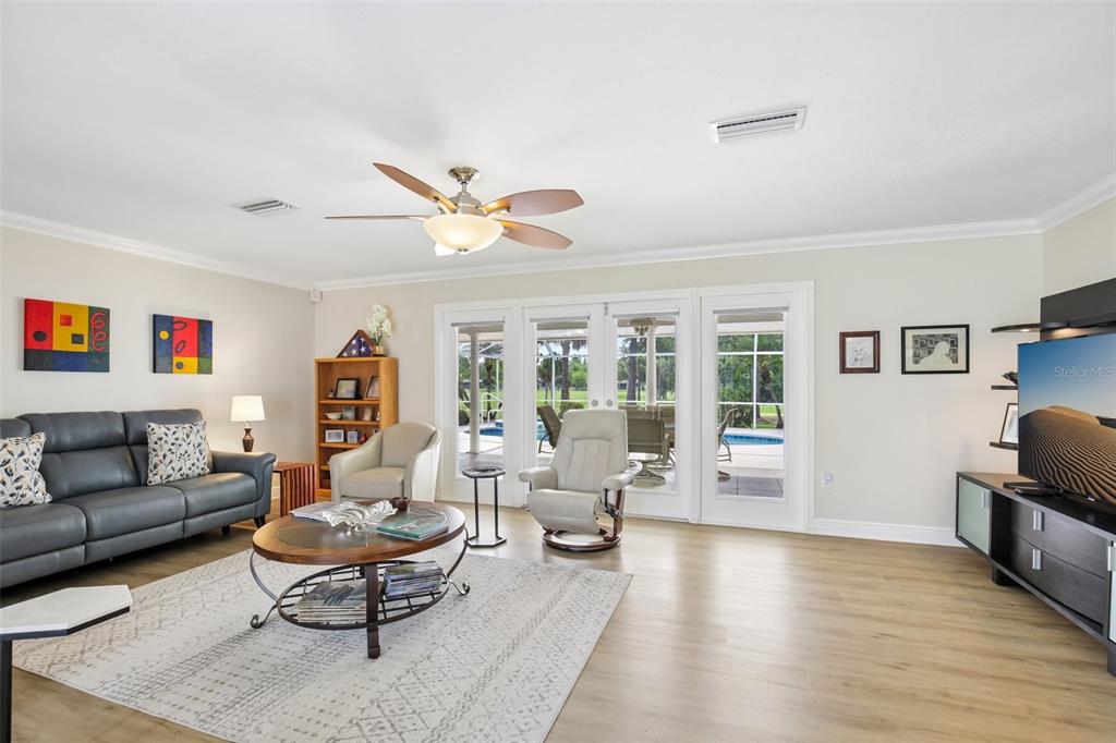 A living room features a grey sofa, two armchairs, a coffee table, and glass doors — 530 MAGELLAN DRIVE, SARASOTA, FL