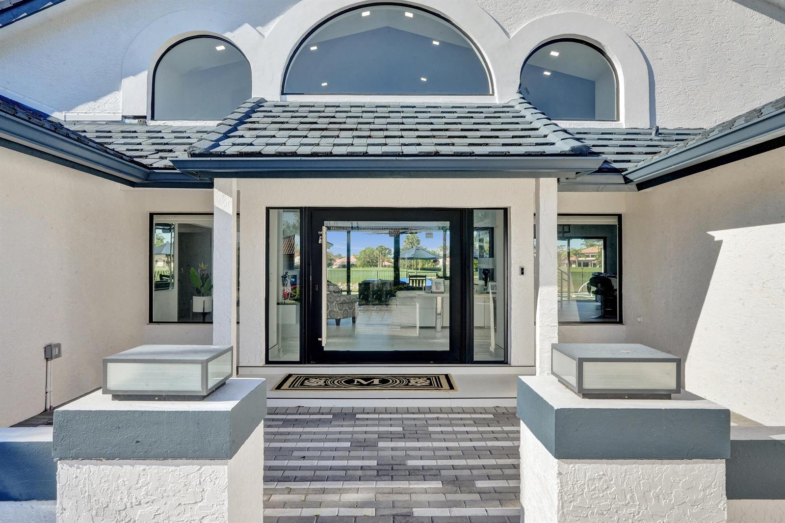 The exterior of a white house features a glass front door and arched windows — 10818 River Glenn Drive, Boca Raton FL 33428, BOCA RATON, FL