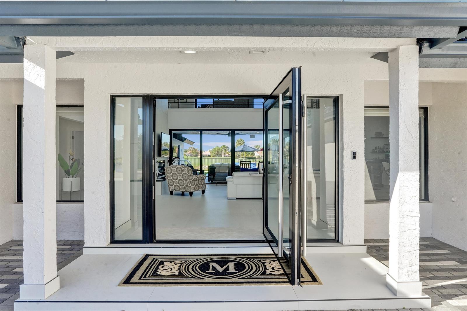 A modern entryway with a glass door, a monogrammed mat, and a view into the home — 10818 River Glenn Drive, Boca Raton FL 33428, BOCA RATON, FL