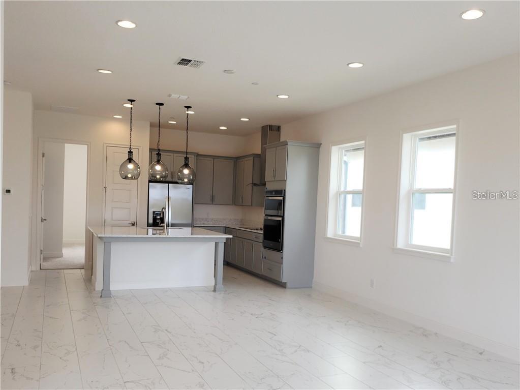 A modern kitchen features gray cabinets, a white island, and marble-look tile flooring — 9467 MERE PARKWAY, ORLANDO, FL