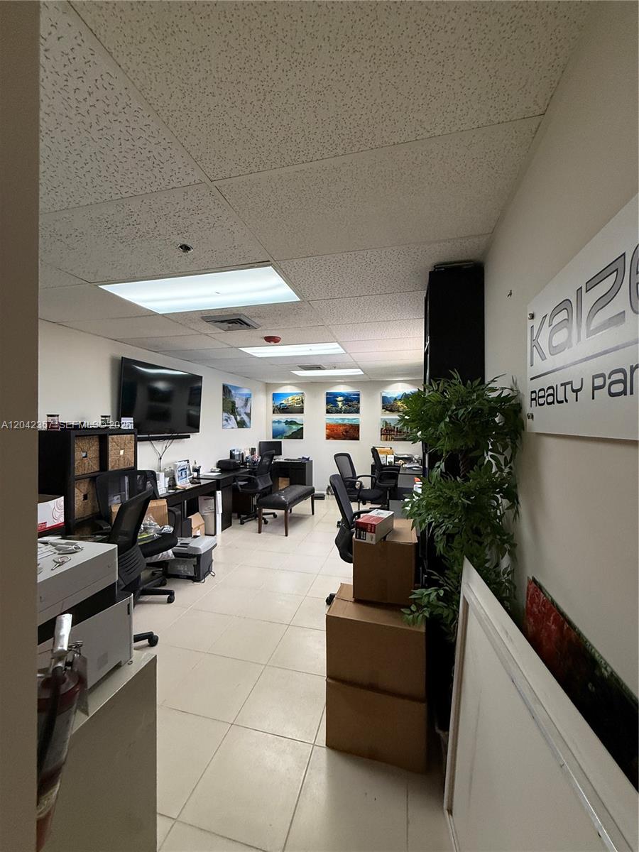 An office space features tiled floors, multiple workstations, wall-mounted televisions, and framed landscape artwork — 9600 NW 25th St # 4H, Doral FL 33172, DORAL, FL