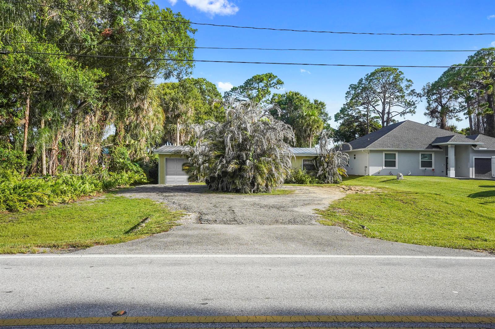 A gravel driveway leads to a house partially obscured by a large, overgrown palm tree — 203 E Easy Street, Fort Pierce FL 34982, FORT PIERCE, FL