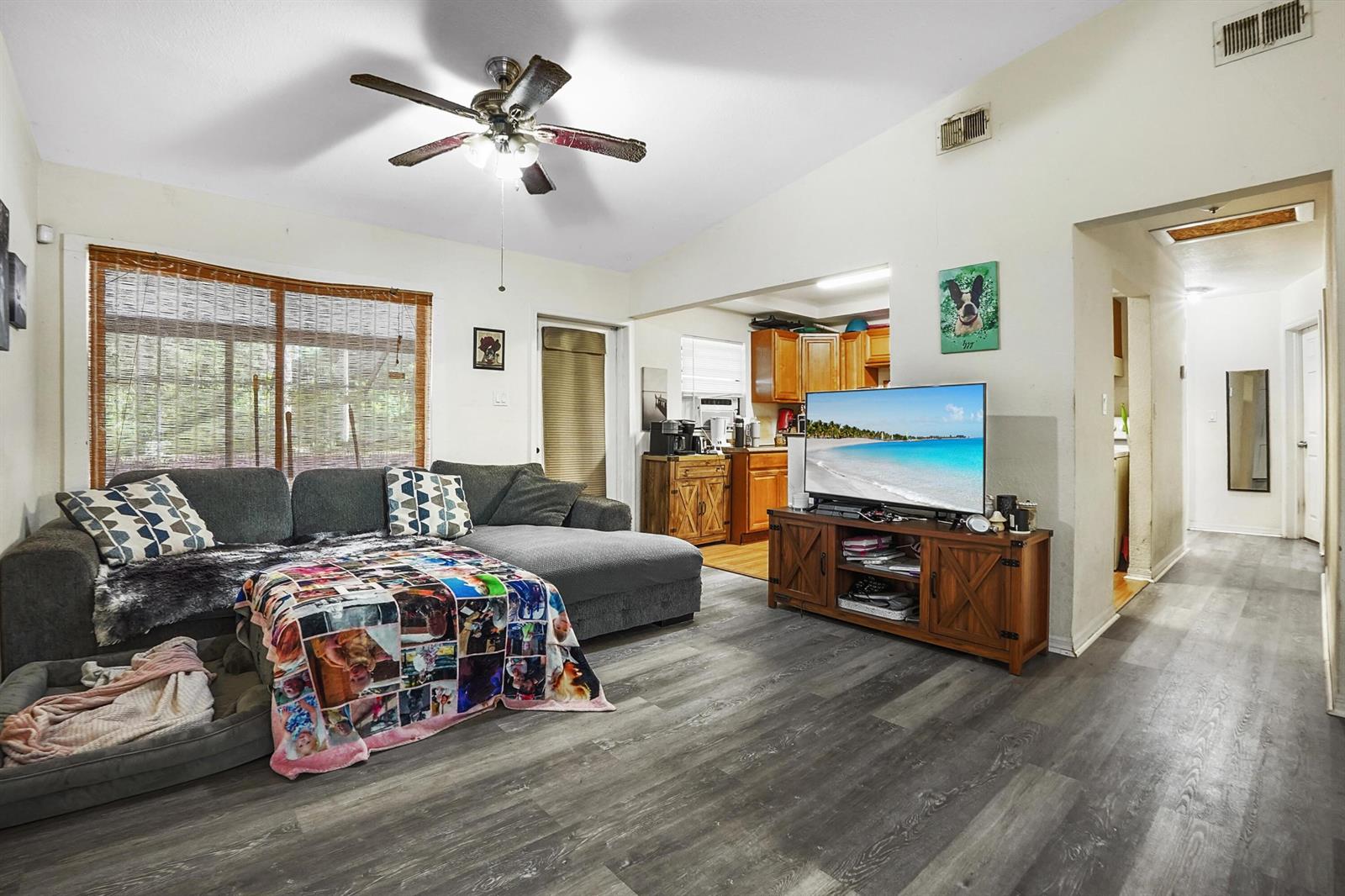 A living room features gray wood-look flooring, a sectional sofa, and an open kitchen view — 203 E Easy Street, Fort Pierce FL 34982, FORT PIERCE, FL