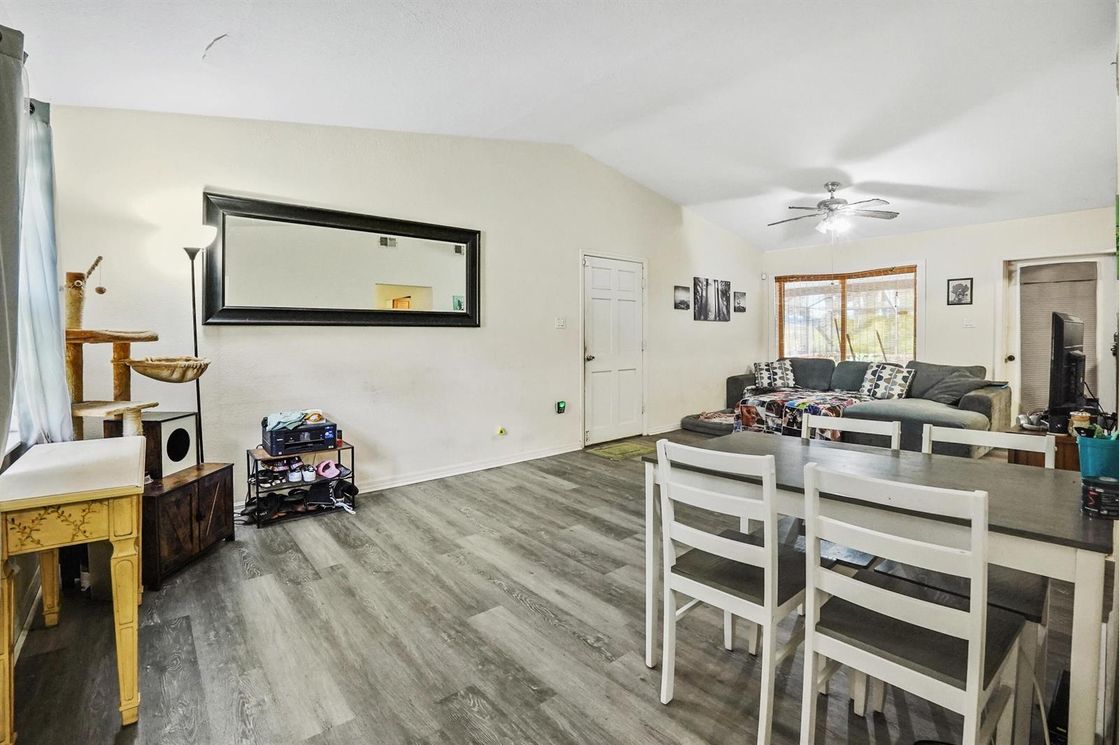 A living and dining area features vaulted ceilings, gray wood-look flooring, and a large mirror — 203 E Easy Street, Fort Pierce FL 34982, FORT PIERCE, FL