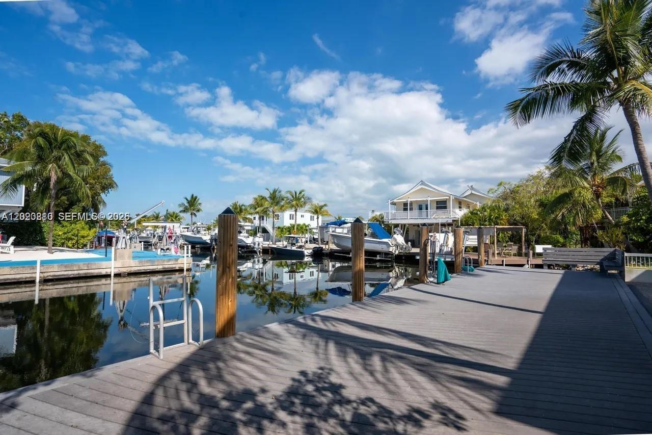A wooden dock extends over a canal lined with boats and waterfront houses — KEY LARGO, FL