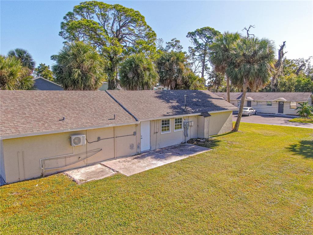 An exterior view of a single-story building with a tan stucco facade and shingled roof — 7618 US HIGHWAY 19, NEW PORT RICHEY, FL