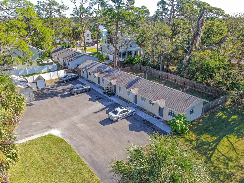 An aerial view shows a single-story apartment building with a parking lot and surrounding trees — 7618 US HIGHWAY 19, NEW PORT RICHEY, FL