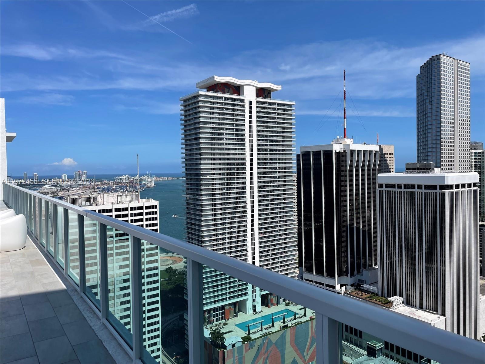 A high-rise balcony overlooks a city skyline, a harbor, and several tall office buildings — 133 NE 2nd Ave # 1007, Miami FL 33132, MIAMI, FL