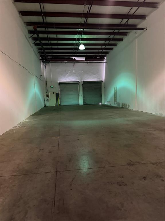 An empty warehouse space features a concrete floor, white walls, and two roll-up doors — 4333 SILVER STAR ROAD UNIT 155, ORLANDO, FL