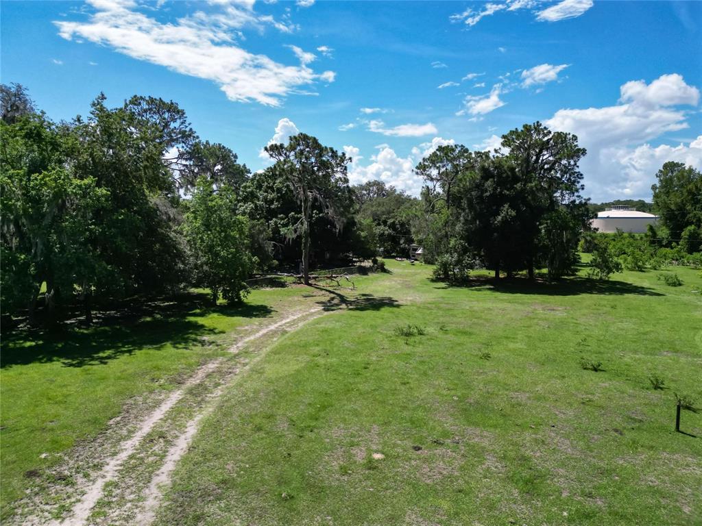 An aerial view of a grassy, partially wooded lot with a dirt path — 8315 TOM COSTINE ROAD, LAKELAND, FL