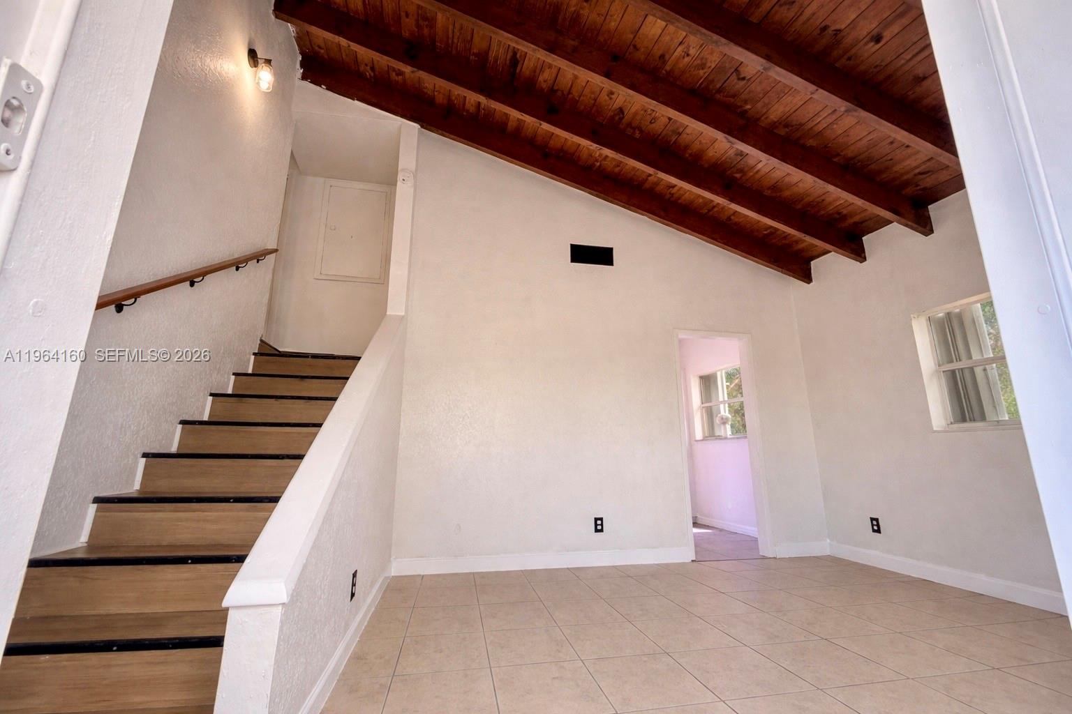 A room with tile flooring, a wooden beamed ceiling, and a staircase leading upward — 640 NW 16th St, Pompano Beach FL 33060, POMPANO BEACH, FL
