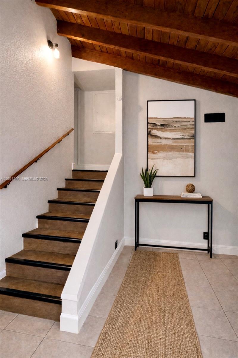 A staircase with wooden treads and a white railing sits beside a console table — 640 NW 16th St, Pompano Beach FL 33060, POMPANO BEACH, FL