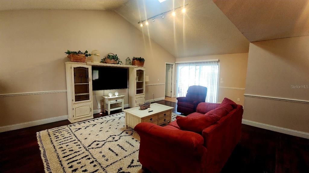 A living room features a vaulted ceiling, a red sofa, and a patterned area rug — 10 BLACKFOOT COURT, PALM COAST, FL