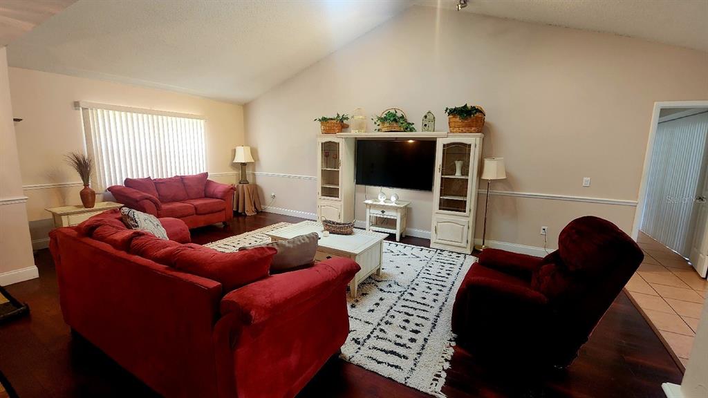 A living room features a vaulted ceiling, red furniture, a white entertainment center, and area rug — 10 BLACKFOOT COURT, PALM COAST, FL