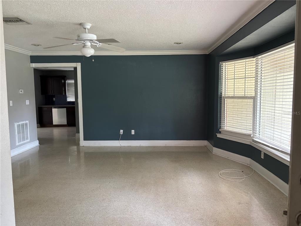 A living room with a dark blue accent wall, light flooring, and a bay window — 2050 HIGH RIDGE DRIVE, CLEARWATER, FL