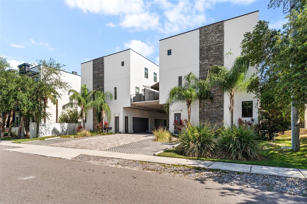 A modern two-story townhouse with white stucco walls, stone accents, and a paved driveway — 4910 W MCELROY AVENUE UNIT 6, TAMPA, FL