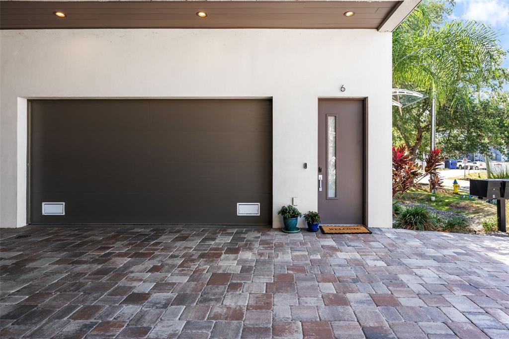 A paved driveway leads to a garage door and a front door with a window — 4910 W MCELROY AVENUE UNIT 6, TAMPA, FL
