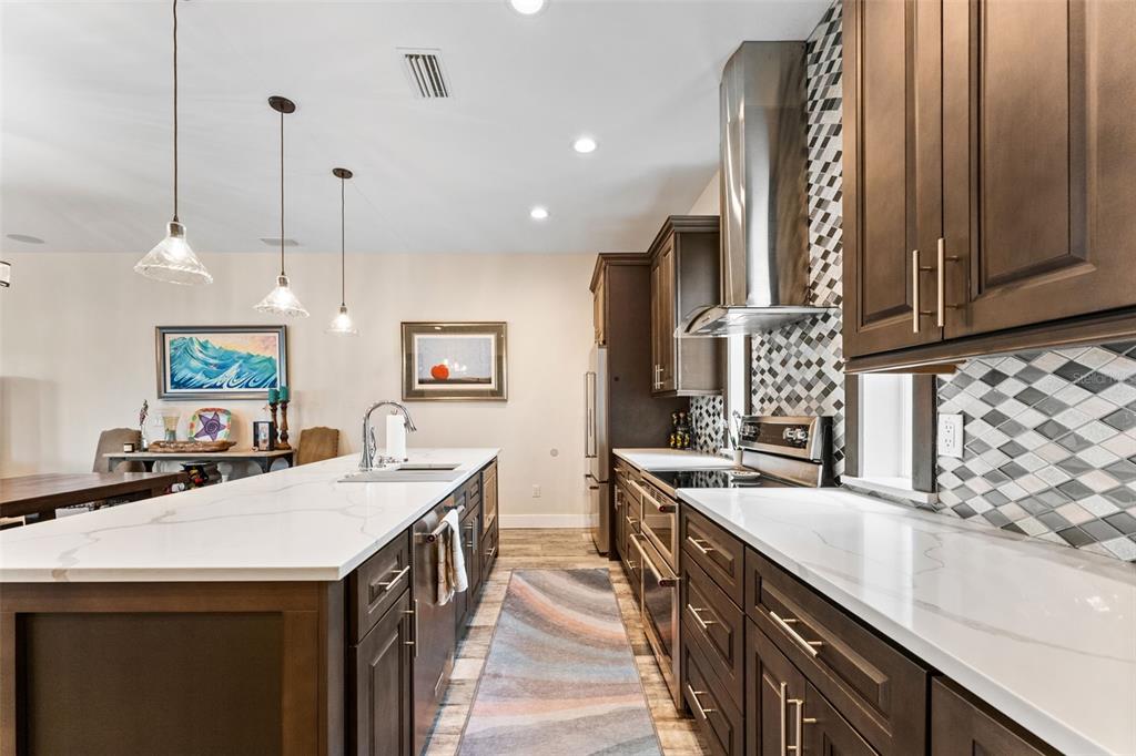 A modern kitchen features dark wood cabinetry, white quartz countertops, and a patterned tile backsplash — 4910 W MCELROY AVENUE UNIT 6, TAMPA, FL