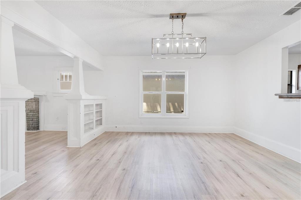 A bright, empty dining room features light wood-look flooring, white walls, and a rectangular chandelier — 1029 COLYER STREET, ORLANDO, FL