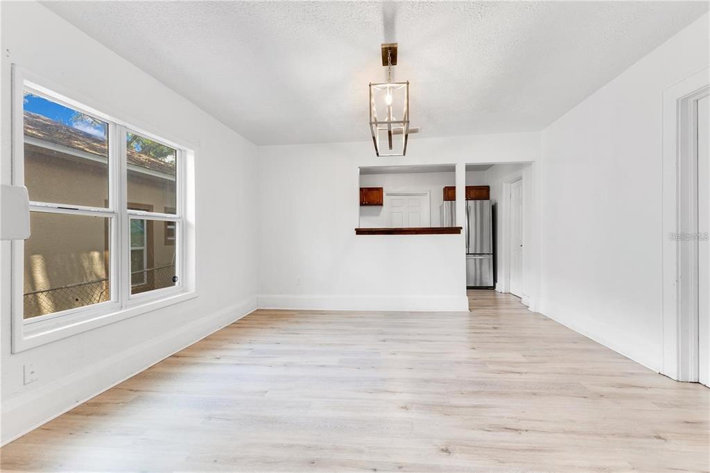 A dining room with white walls, light wood flooring, and a rectangular metal pendant light — 1029 COLYER STREET, ORLANDO, FL