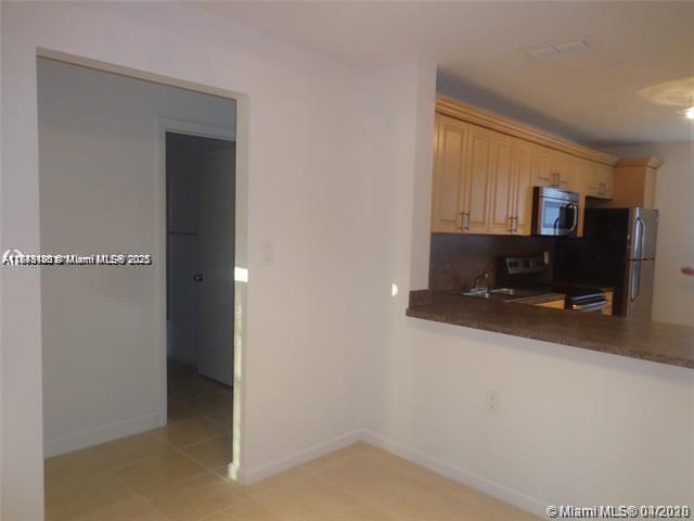 A kitchen with light wood cabinets and a breakfast bar overlooks a tiled floor area — 2276 SW 81st Ave # 2276, Miramar FL 33025, MIRAMAR, FL
