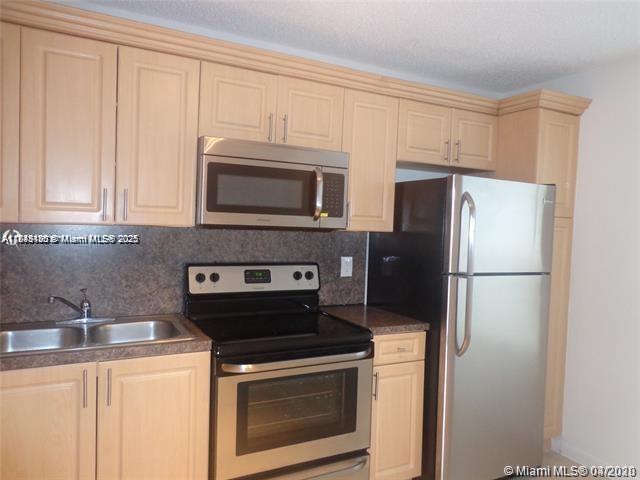 A kitchen features light wood cabinets, stainless steel appliances, and a dark countertop — 2276 SW 81st Ave # 2276, Miramar FL 33025, MIRAMAR, FL