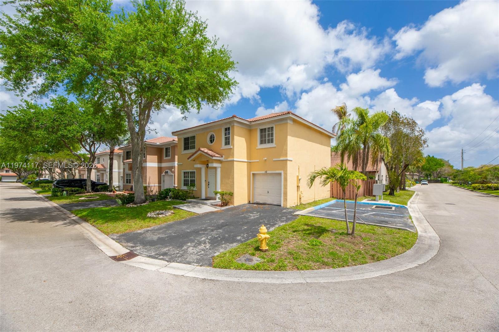 A two-story yellow stucco house with a garage and driveway sits on a corner lot — 10 NW 110th Ave, Plantation FL 33324, PLANTATION, FL