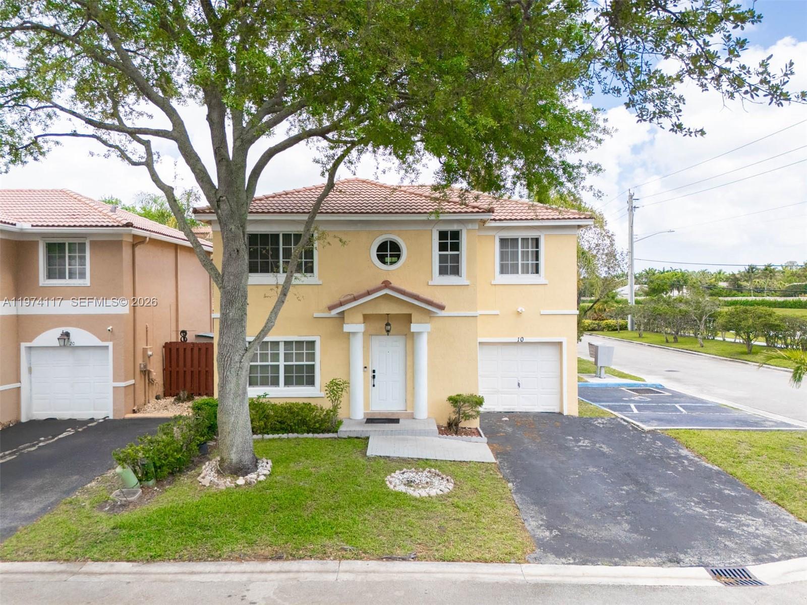 The exterior of a two-story yellow house features a tiled roof and a driveway — 10 NW 110th Ave, Plantation FL 33324, PLANTATION, FL