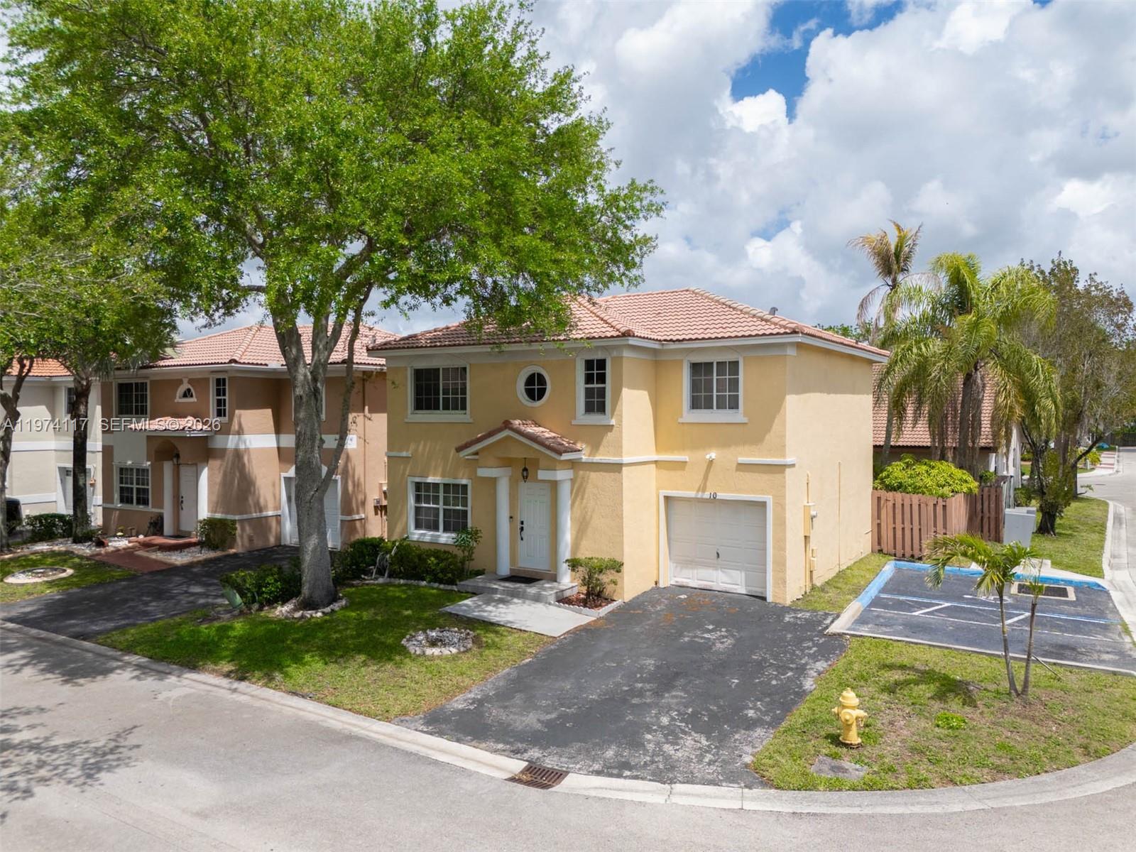An exterior view of a two-story yellow house with a garage and a driveway — 10 NW 110th Ave, Plantation FL 33324, PLANTATION, FL