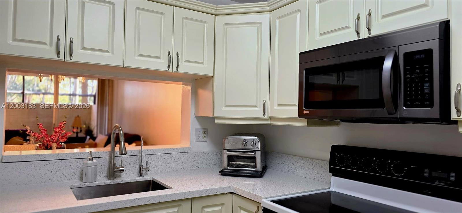 A kitchen features white cabinets, a black microwave, a stainless steel sink, and light countertops — 10835 SW 112th Ave # 106, Miami FL 33176, MIAMI, FL