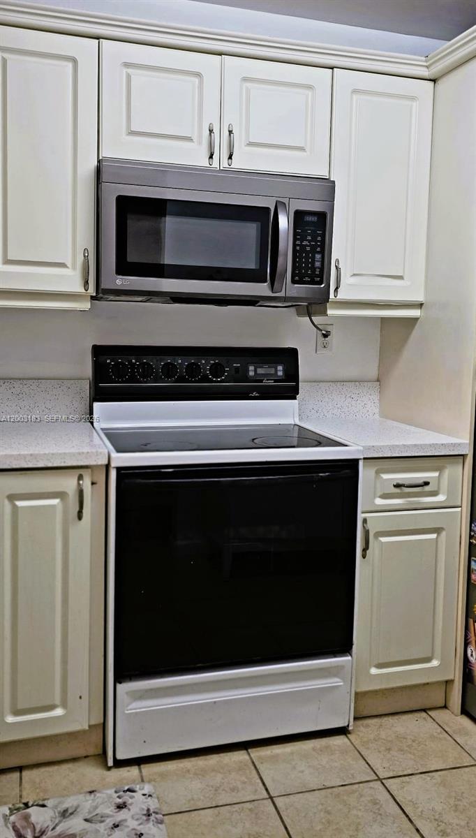 A kitchen features white cabinets, a black electric range, and a stainless steel microwave — 10835 SW 112th Ave # 106, Miami FL 33176, MIAMI, FL