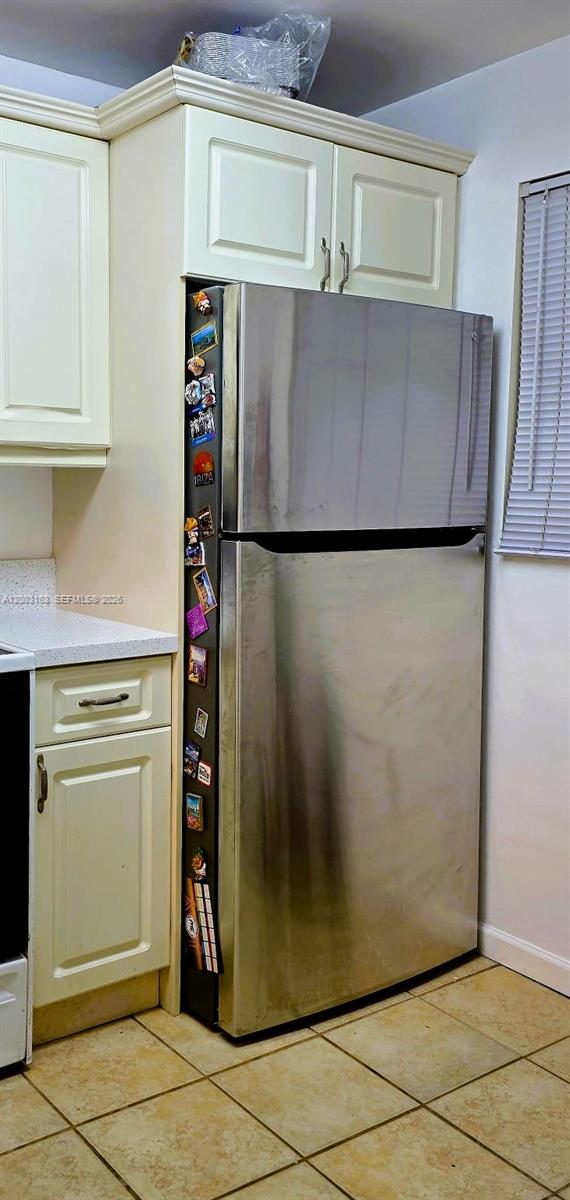 A stainless steel refrigerator sits between cream-colored kitchen cabinets on a tiled floor — 10835 SW 112th Ave # 106, Miami FL 33176, MIAMI, FL