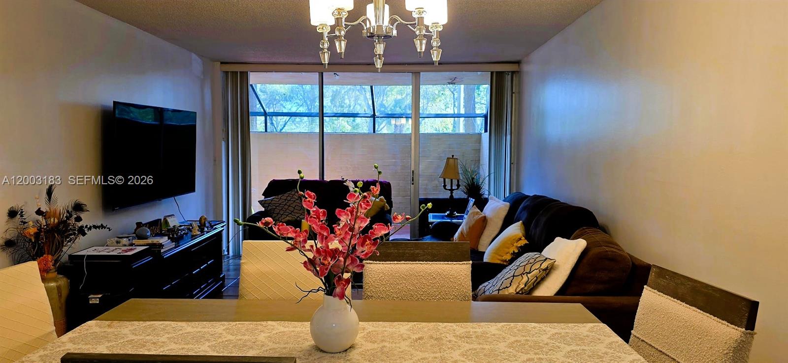 A dining area with a floral centerpiece leads into a living room with a balcony — 10835 SW 112th Ave # 106, Miami FL 33176, MIAMI, FL