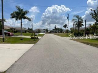 A paved residential street lined with palm trees under a blue sky with white clouds — 214 SW 43 LANE, CAPE CORAL, FL