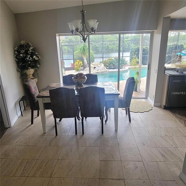 A dining area with tile floors, a chandelier, and sliding doors overlooking a pool — 2391 WINDWARD COVE, KISSIMMEE, FL