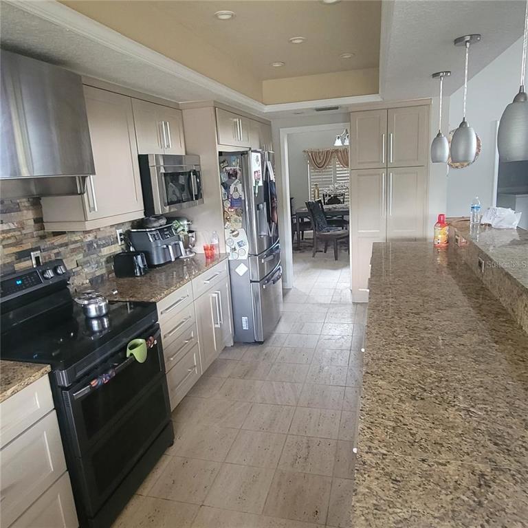 A kitchen with light-colored cabinets, granite countertops, stainless steel appliances, and a breakfast bar — 2391 WINDWARD COVE, KISSIMMEE, FL