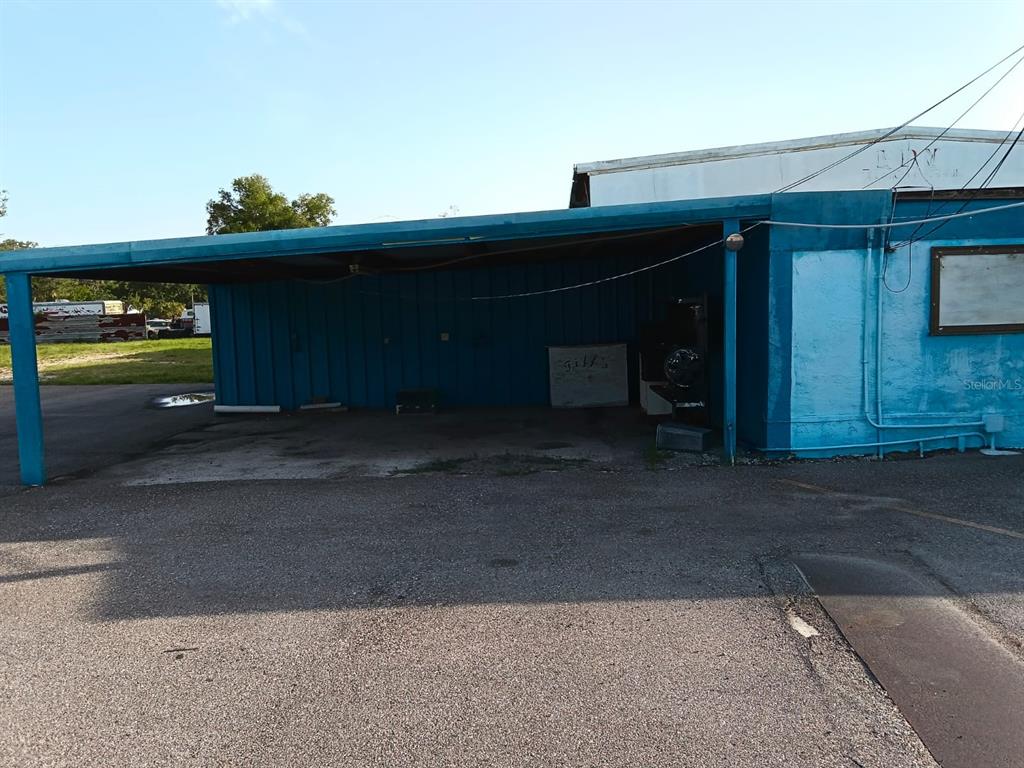 A blue exterior building features a large covered parking area with a concrete floor — 9006 GIBSONTON DRIVE, GIBSONTON, FL