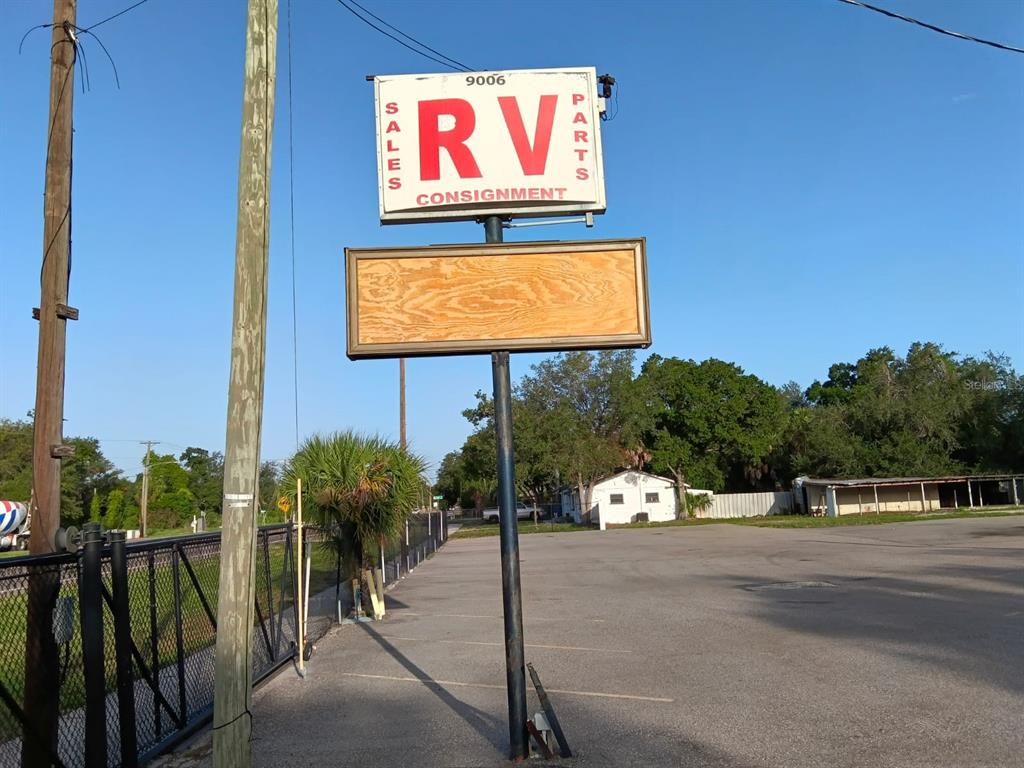 A sign for an RV sales, parts, and consignment business stands in a paved lot — 9006 GIBSONTON DRIVE, GIBSONTON, FL