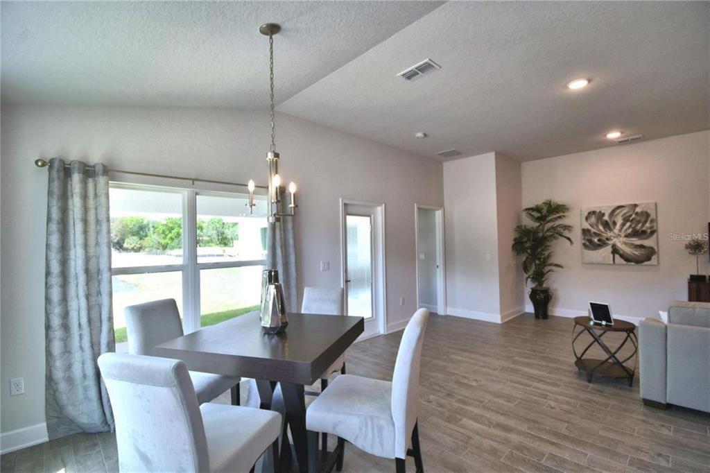 A dining area with a dark wood table, light chairs, and tile flooring — 2413 NW 23RD AVENUE, OCALA, FL