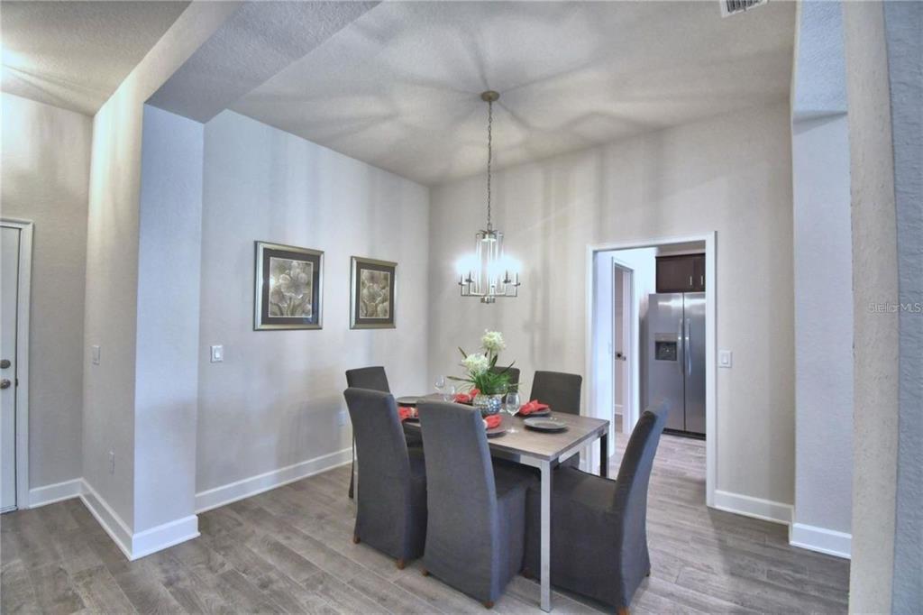 A dining room features a rectangular table with six gray chairs under a chandelier — 2413 NW 23RD AVENUE, OCALA, FL