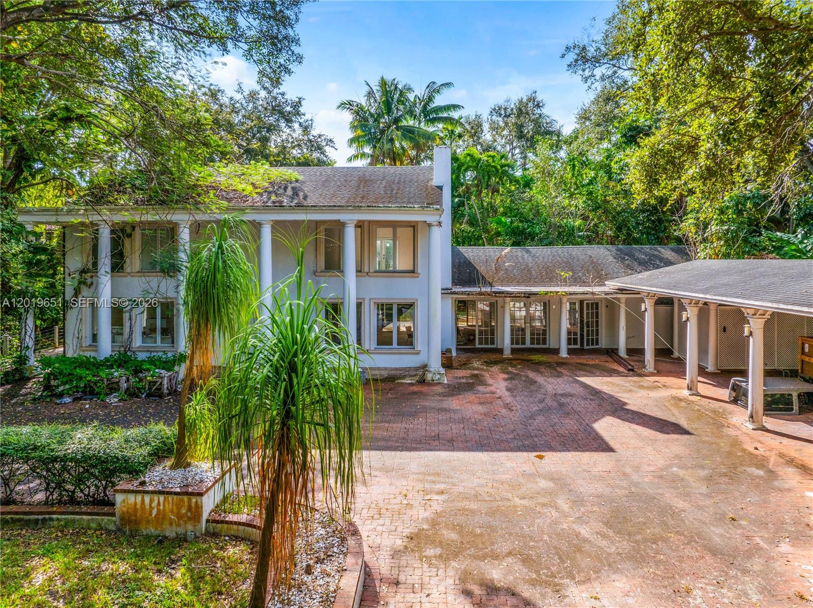 A two-story white house with columns and a brick driveway surrounded by lush trees — 3720 Poinciana Ave, Miami FL 33133, MIAMI, FL