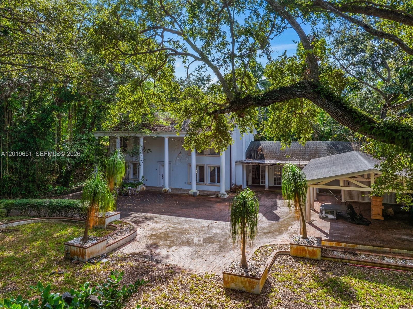 An exterior view of a two-story white house with columns and a brick courtyard — 3720 Poinciana Ave, Miami FL 33133, MIAMI, FL