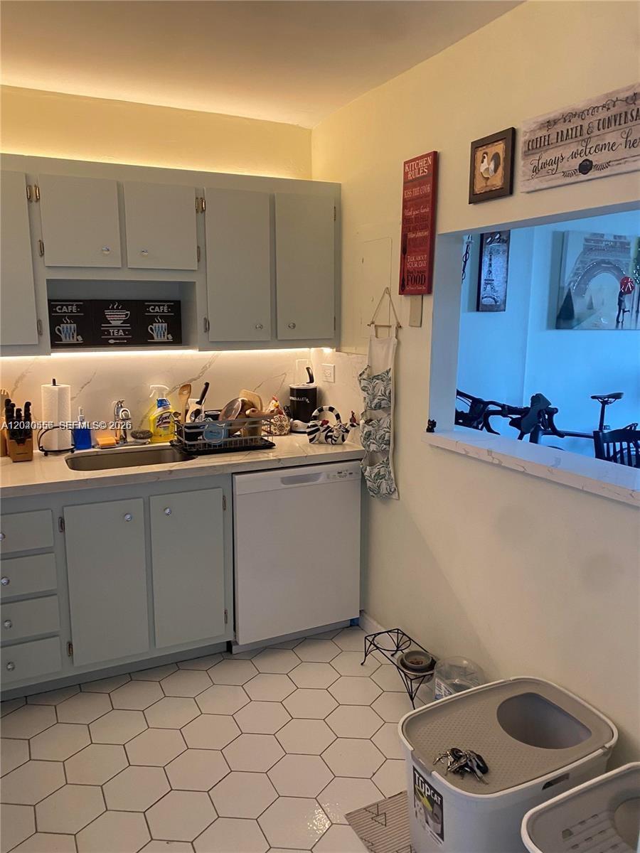 A kitchen features light blue cabinets, white countertops, a white dishwasher, and hexagonal floor tiles — 1465 NE 123rd St # 409, North Miami FL 33161, NORTH MIAMI, FL