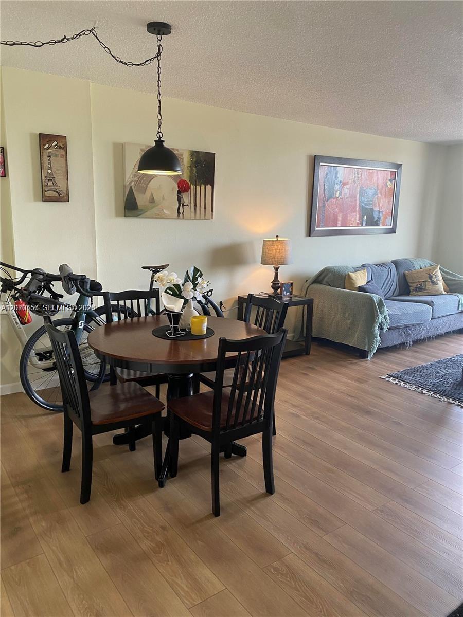 A dining area with a round table and chairs sits adjacent to a living room — 1465 NE 123rd St # 409, North Miami FL 33161, NORTH MIAMI, FL