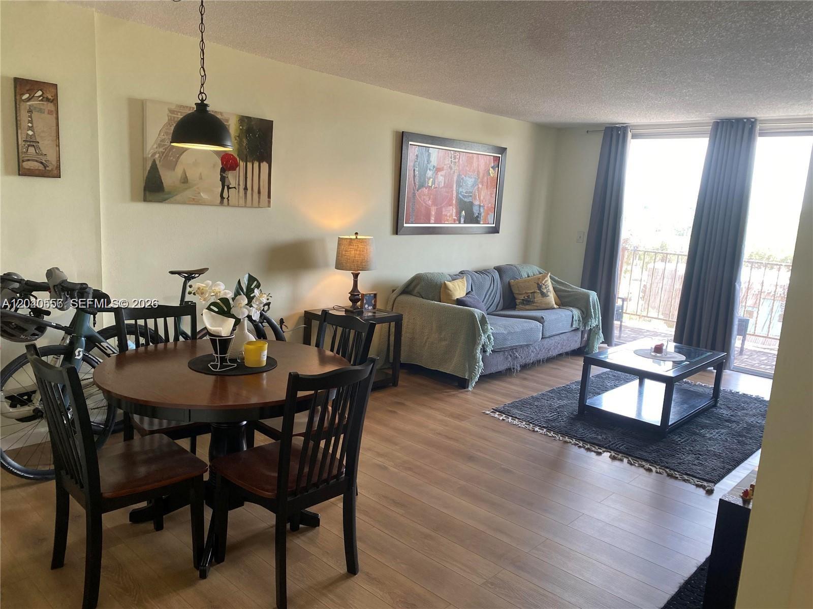 A living and dining area features wood-look flooring, a round table, and a sofa — 1465 NE 123rd St # 409, North Miami FL 33161, NORTH MIAMI, FL