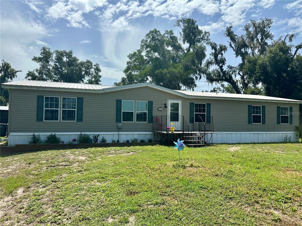 A single-story manufactured home with light gray siding and dark shutters sits on a lawn — 8528 AVON LADY PLACE, PLANT CITY, FL