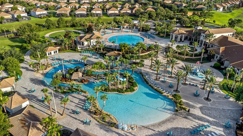 An aerial view shows a large resort-style swimming pool complex with palm trees and buildings — 9039 SHADOW MOUNTAIN STREET, DAVENPORT, FL