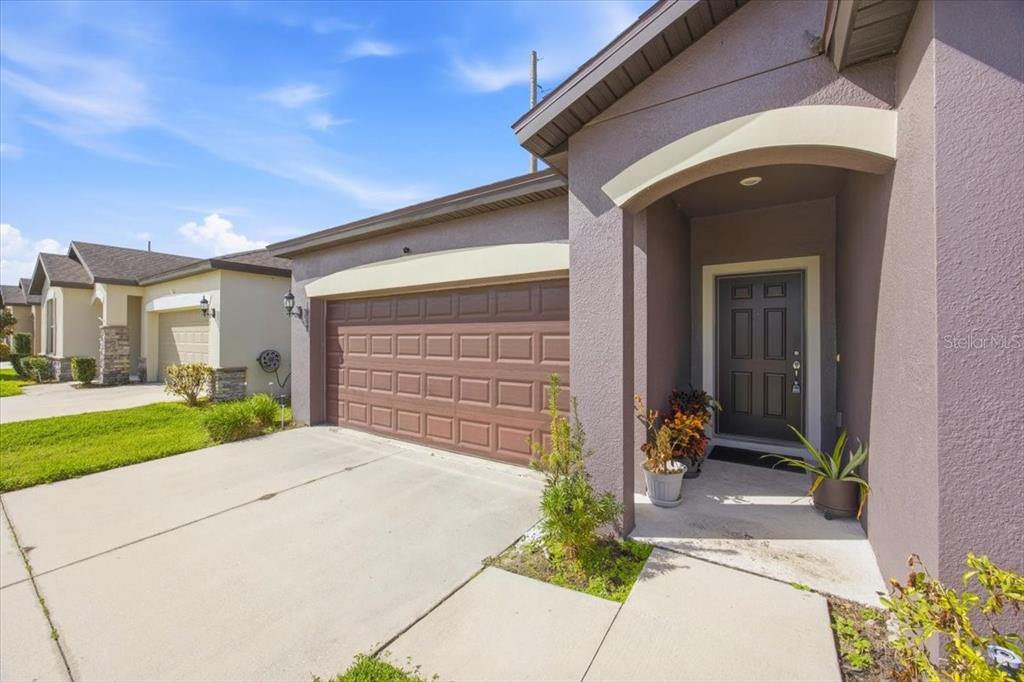 A view of a house exterior featuring a brown garage door and a covered entryway — 1917 CAYMAN COVE CIRCLE, ST CLOUD, FL